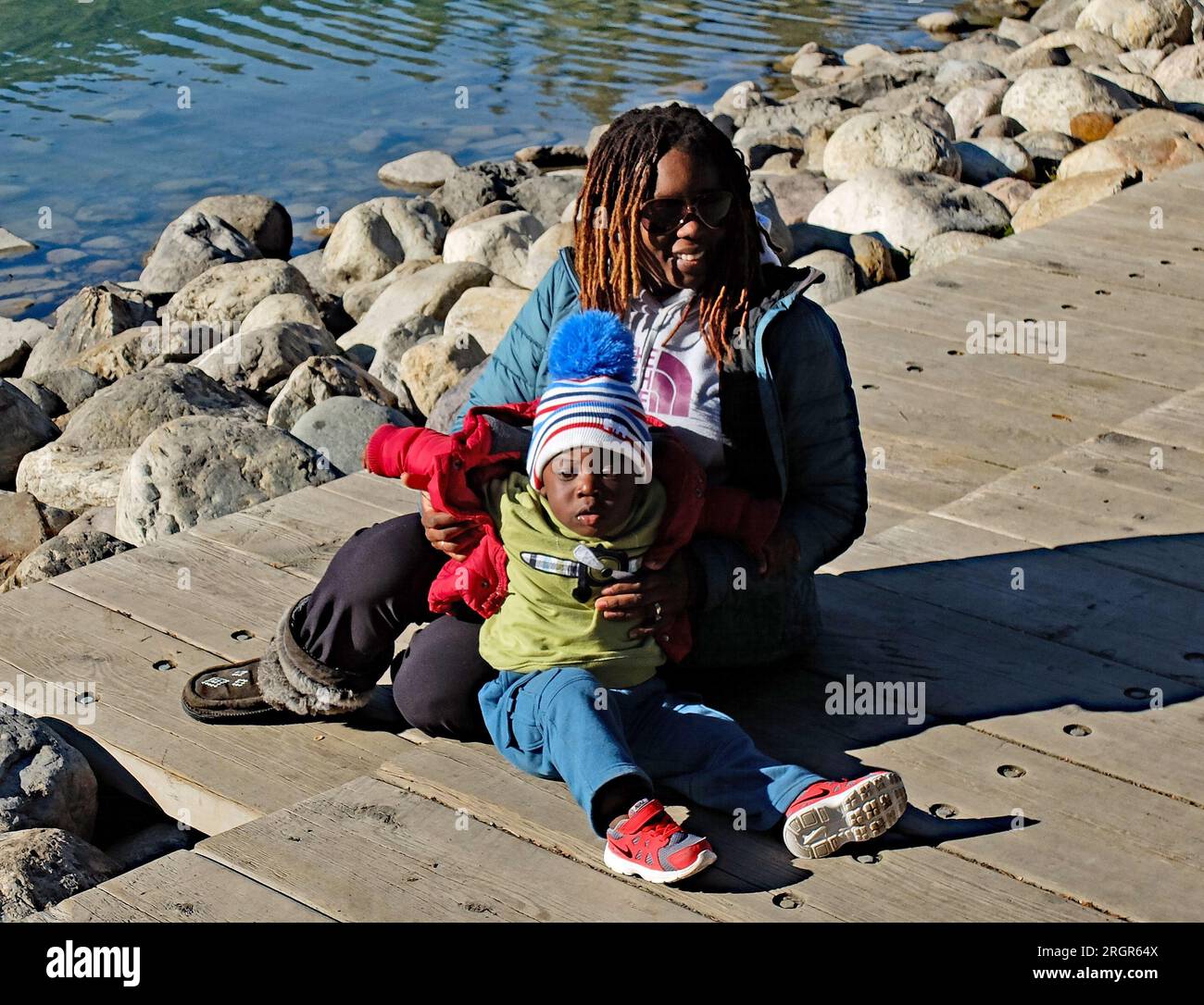 Lake Louise, Alberta, Kanada – 14 2013. Oktober eine afroamerikanische Frau, die mit ihrem Kleinkind für einen Fotografen am Lake Louise posiert Stockfoto