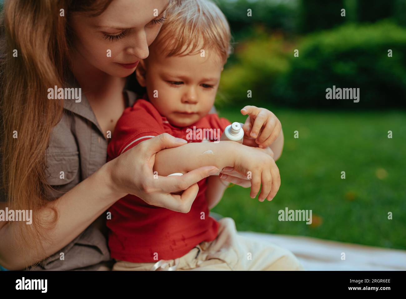 Mutter legt im Sommer Sahne auf die Hand des Babys Stockfoto