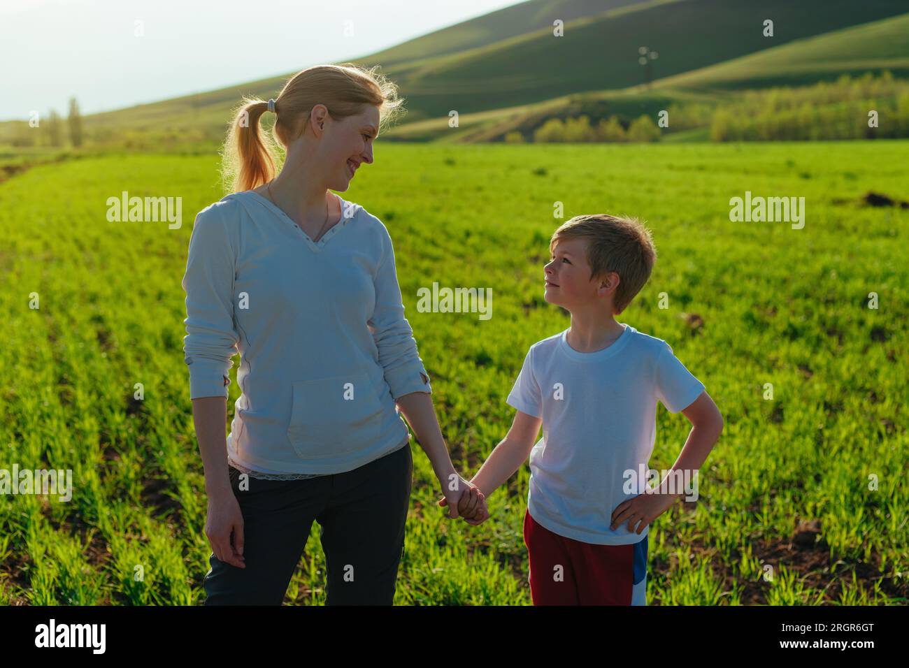 Glückliche Mutter und Sohn auf dem Feld, die sich an einem sonnigen Tag ansehen Stockfoto