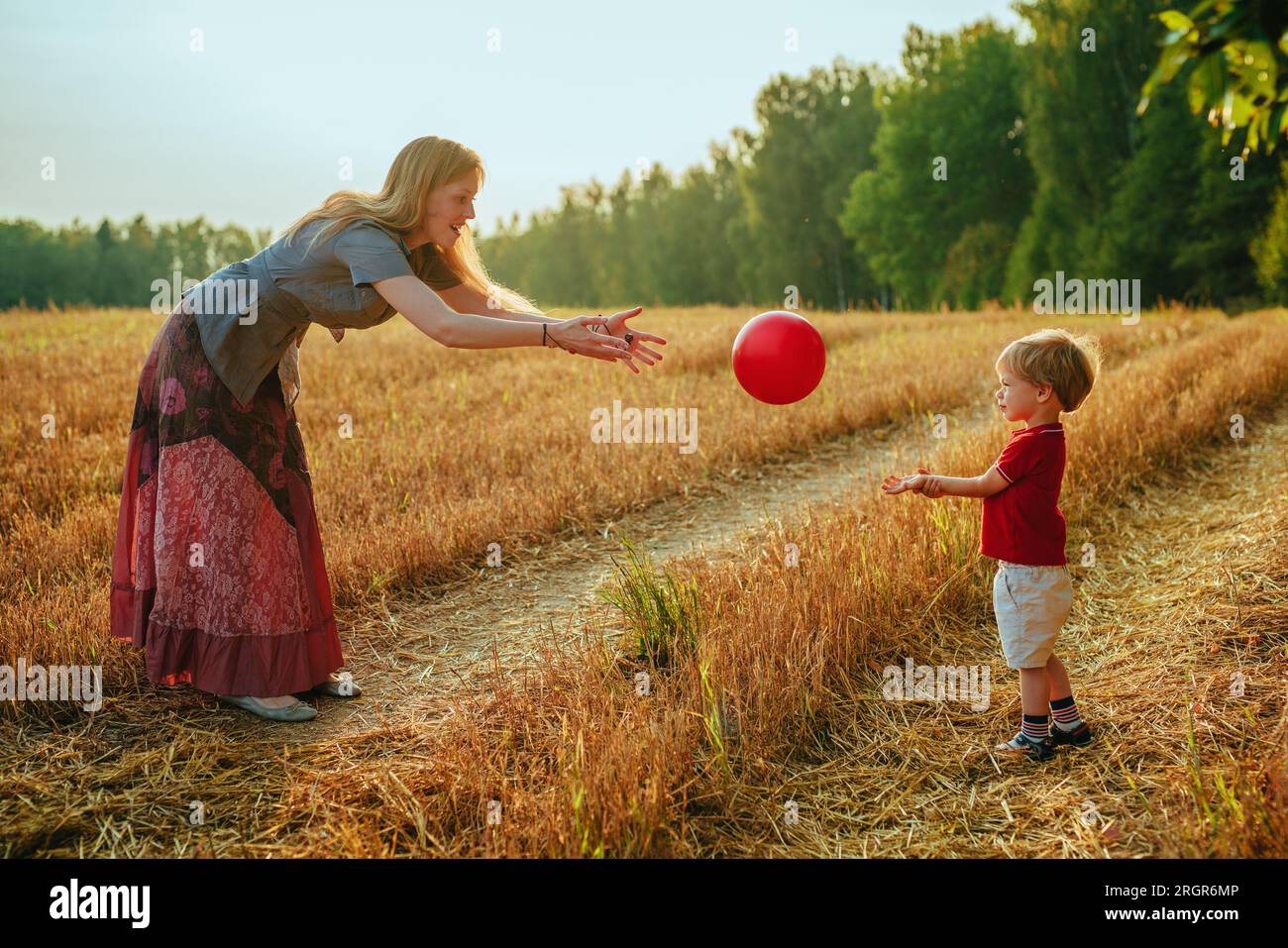Junge Mutter spielt mit ihrem zweijährigen Sohn Ball auf einem Feld Stockfoto