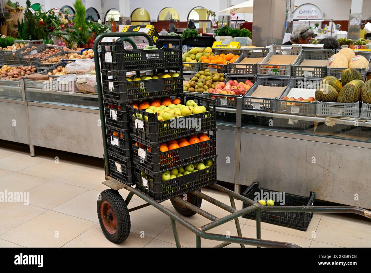 Trolley mit Obstkartons zum Auffüllen im lokalen Markt Mercado Coletivo Aveiro mit Verkaufsständen, die frisches Obst, Gemüse, Portugal, verkaufen Stockfoto