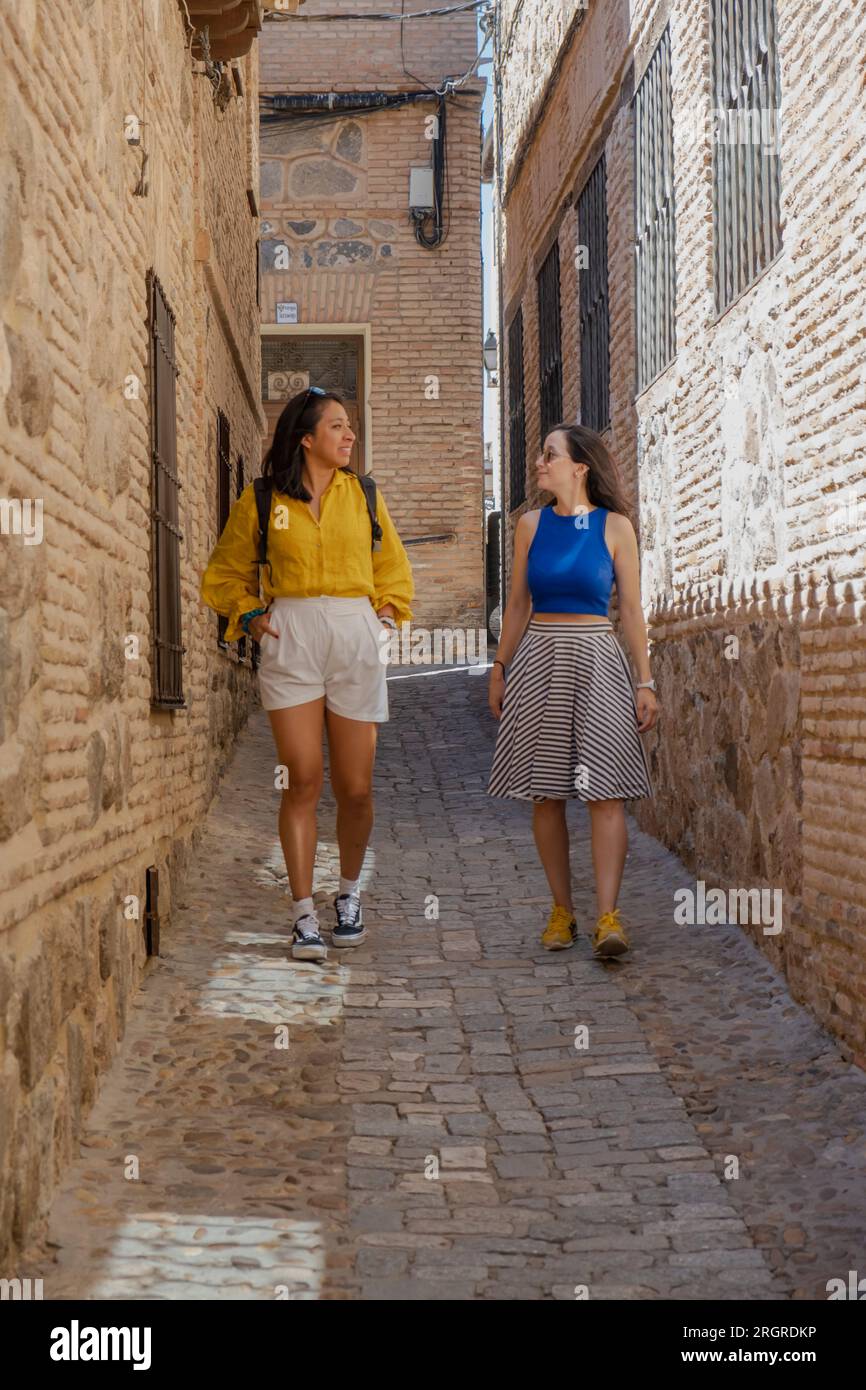 Zwei Freundinnen erkunden die mittelalterliche Stadt Toledo in Spanien. Touristen, die durch die engen Gassen laufen. Stockfoto