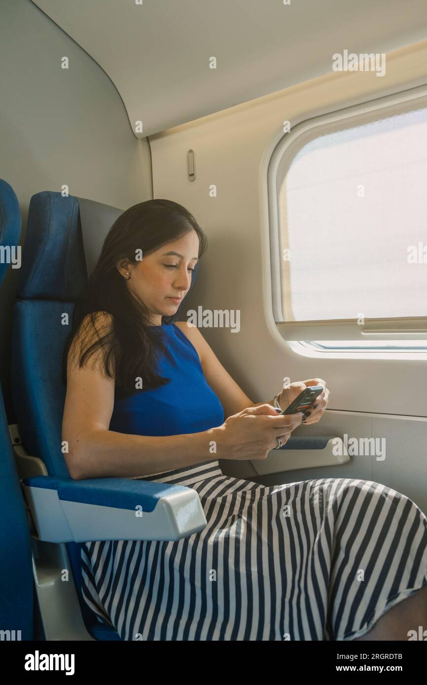 Porträt einer jungen Frau mit Smartphone während der Zugfahrt Stockfoto