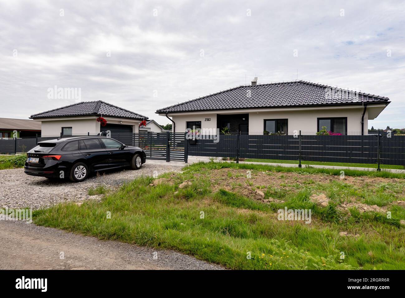 SENOV, TSCHECHISCHE REPUBLIK - 4. AUGUST 2023: Neu gebautes Familienhaus und schwarzer Skoda Octavia Combi Familienwagen. Typischer Vorort in der Nähe von Großstädten. Stockfoto