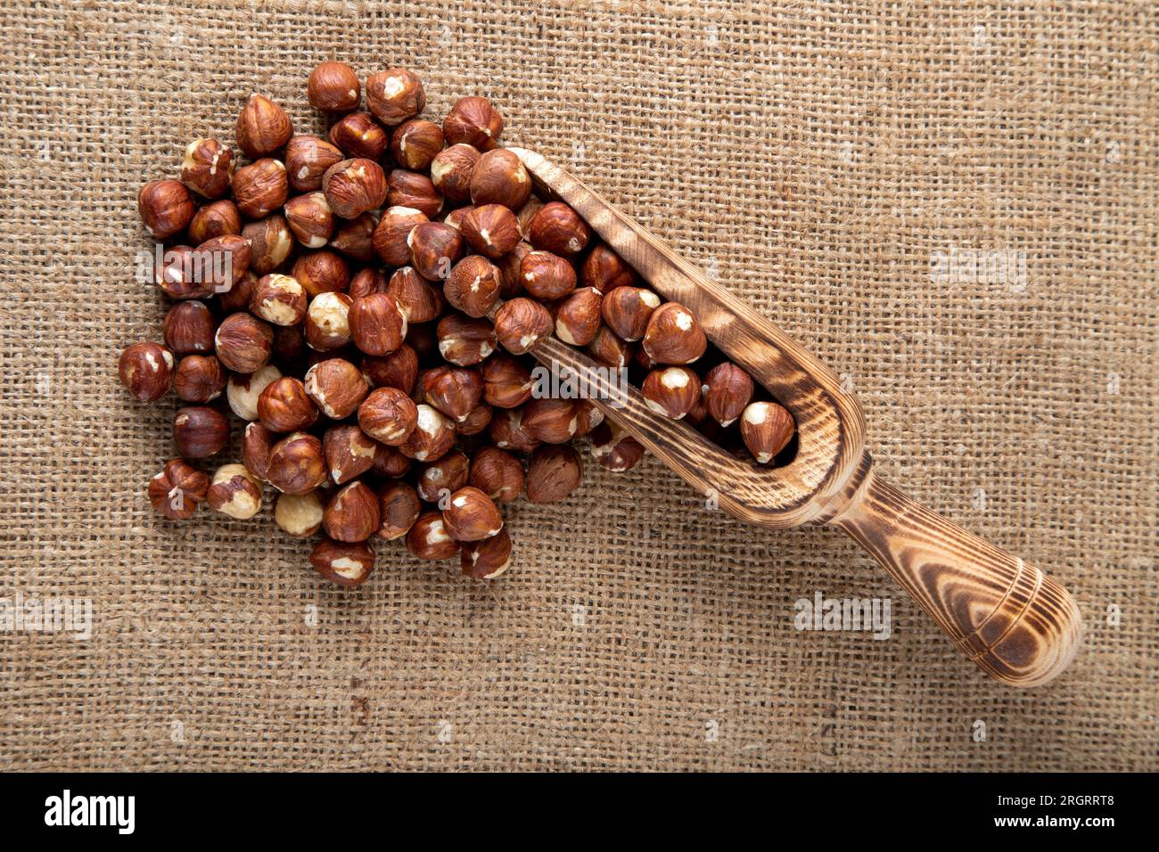 Haselnüsse und Holzschaufel auf rustikalem Hintergrund, Blick von oben Stockfoto