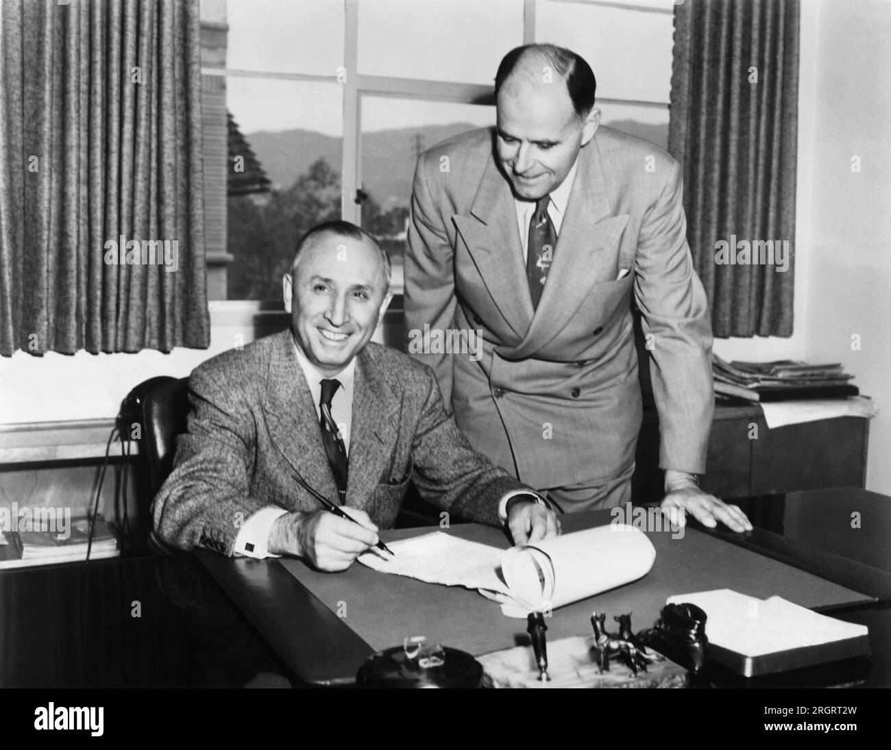 Burbank, Kalifornien: c. 1951 Roy Disney, President von Walt Disney Productions (L), und Jack Harkins (R), President der Lime Cola Company von Chattanooga, Tennessee, unterzeichneten einen Vertrag über eine Reihe von Donald Duck Softdrinks. Stockfoto