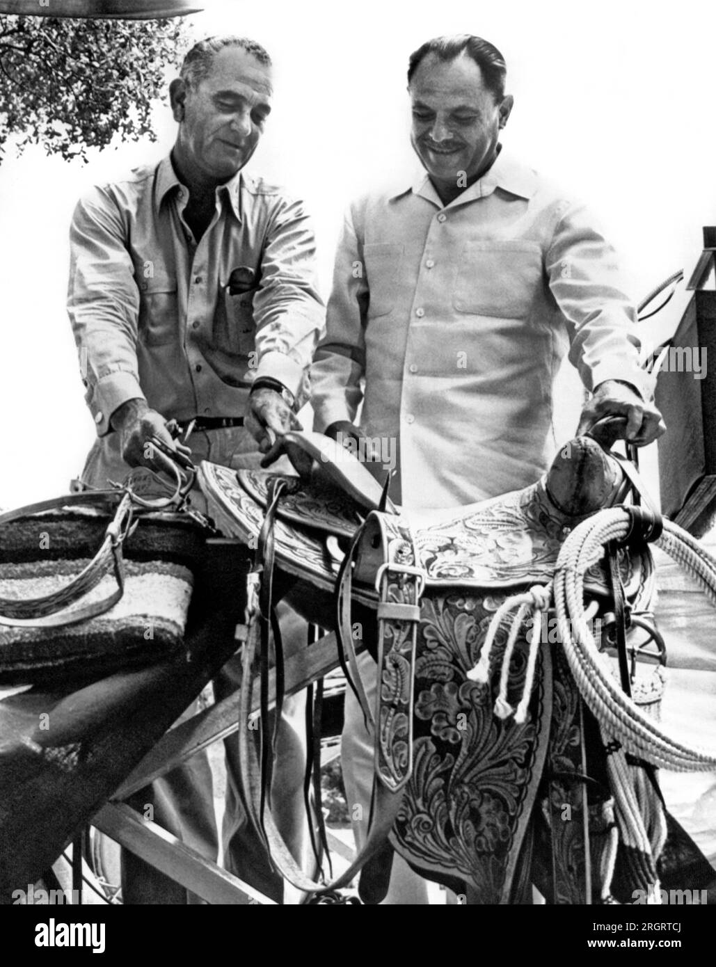 Johnson City, Texas: Am 16. Juli 1961 präsentiert Vizepräsident Lyndon Johnson Präsident Ayub Khan aus Pakistan bei einem Barbecue auf der LBJ Ranch in Texas einen handgefertigten Cowboysattel. Stockfoto