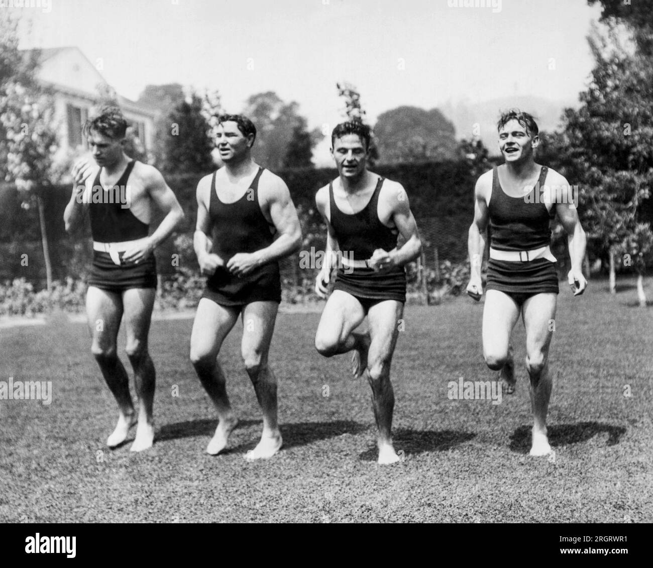 Los Angeles, Kalifornien: c. 1927 Jack Dempsey trainiert in seinem Hof mit L-R, Sprinter Frank Wykoff, Dempsey, Sprinter Frank Lombardi, und der Olympiasieger Bud Houser. Dempsey plant eine Revanche mit Gene Tunney. Stockfoto