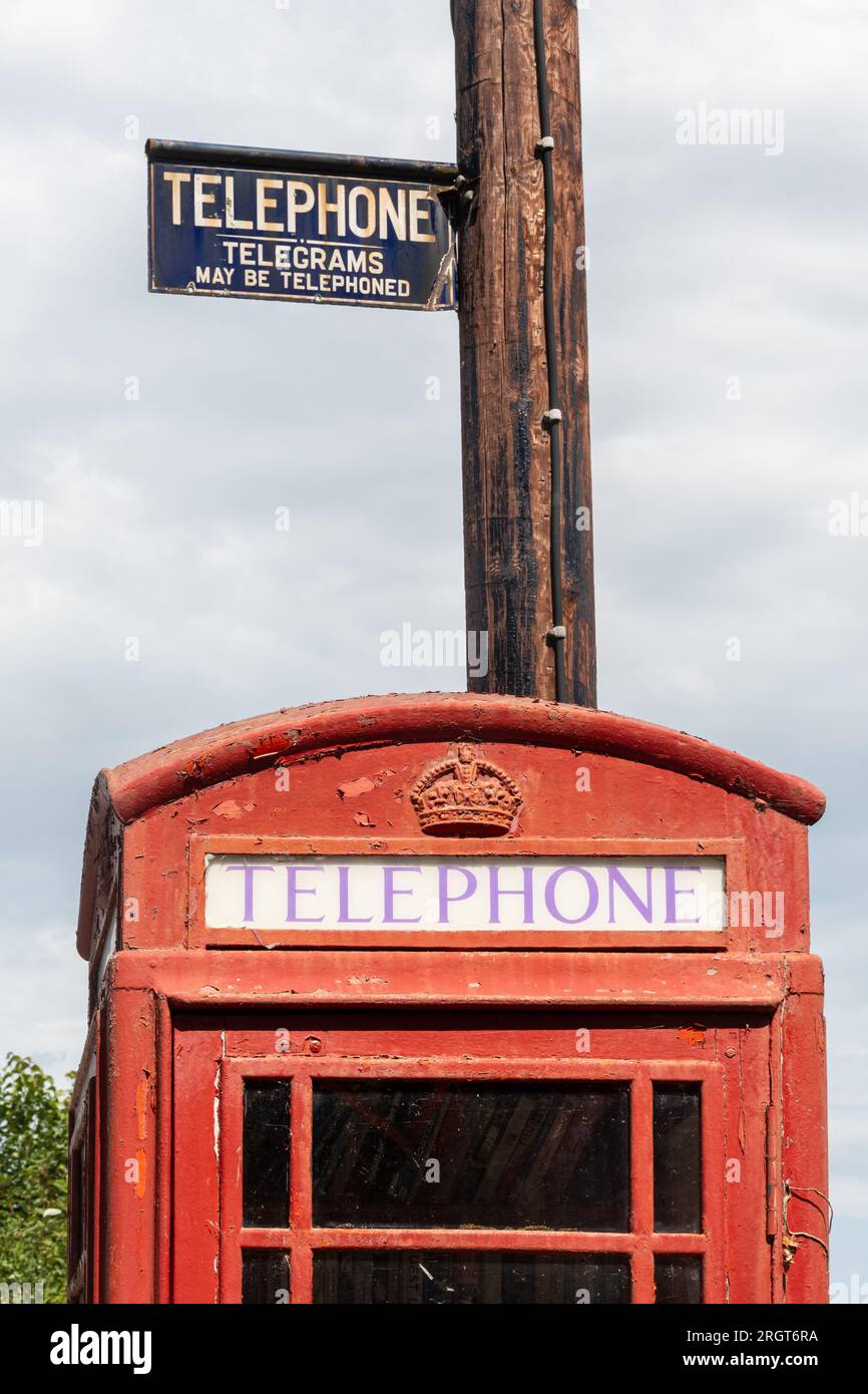 Rote Telefonzelle im Dorf Longstock mit historischem, altem Schild, das TelefonTelegramme liest, können in Hampshire, England, Großbritannien, angerufen werden Stockfoto