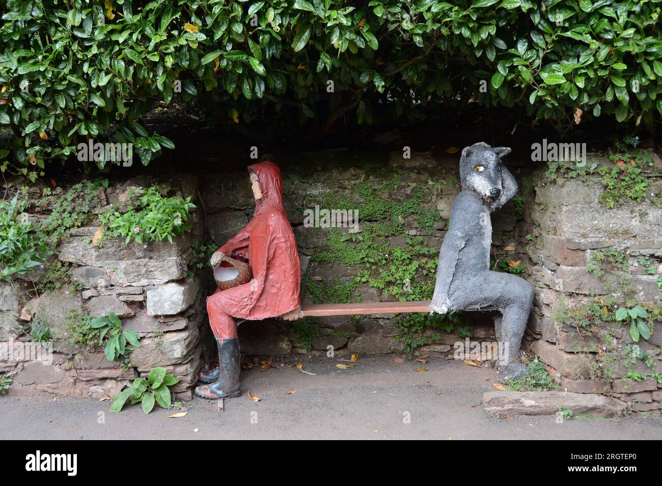 Little Red Riding Hood und der große böse Wolf auf einer Bank am Cockington Court Stockfoto