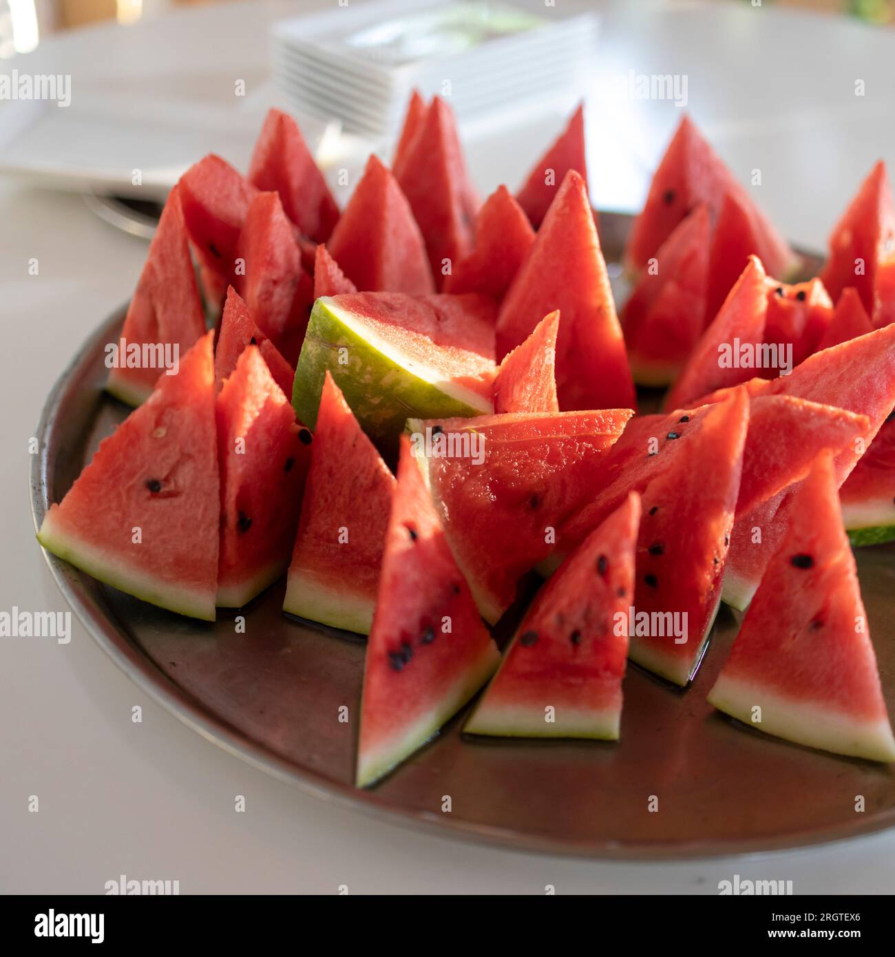 Viele kleine dreieckige Scheiben reifer roter Wassermelone auf einem Teller. Isoliert auf weißem Hintergrund. Blick von oben Stockfoto