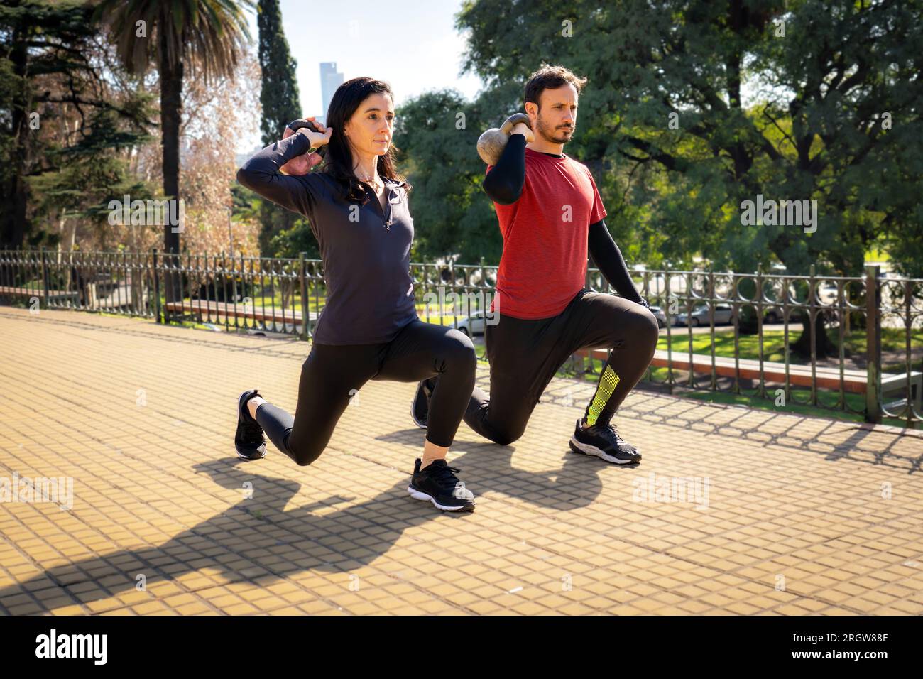 Mann und Frau heben Kettlebells zusammen. Outdoor-Sportkonzept Stockfoto