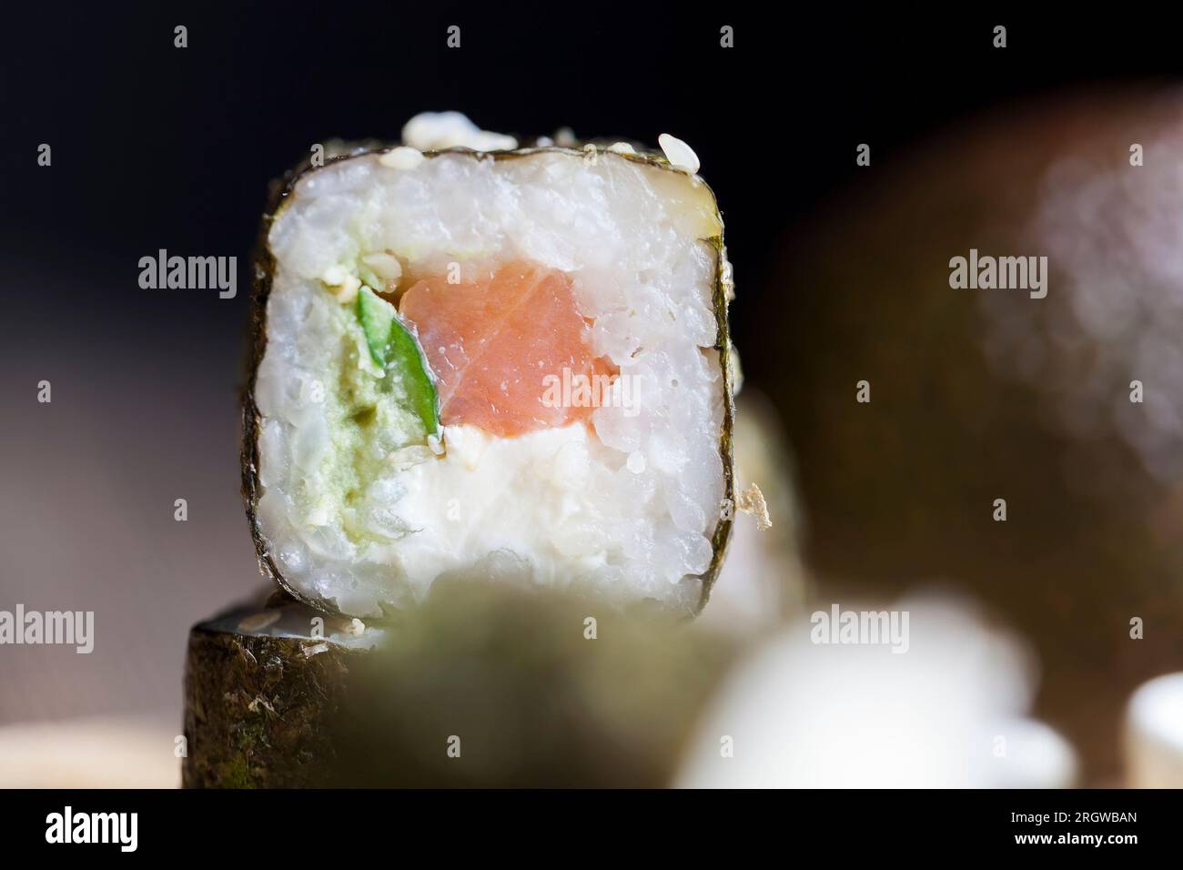Sushi aus weißem Reis, Forelle und Avocado, verzehrfertige pflanzliche Produkte und roter Fischlachs Stockfoto