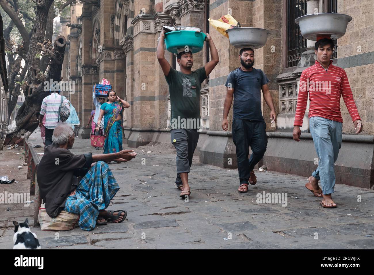 Träger mit Fischtellern auf dem Kopf, vor dem Chhatrapati Shivaji Maharaj Terminus (CMST) in Mumbai, Indien, um die Tabletts mit dem lokalen Zug zu transportieren Stockfoto