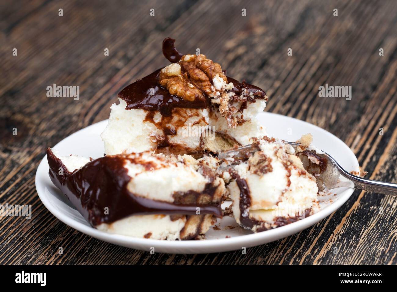 Schokoladencreme-überzogener Cremetorte mit Biskuitkuchen, würfelförmiger Kuchen auf einem Teller Stockfoto