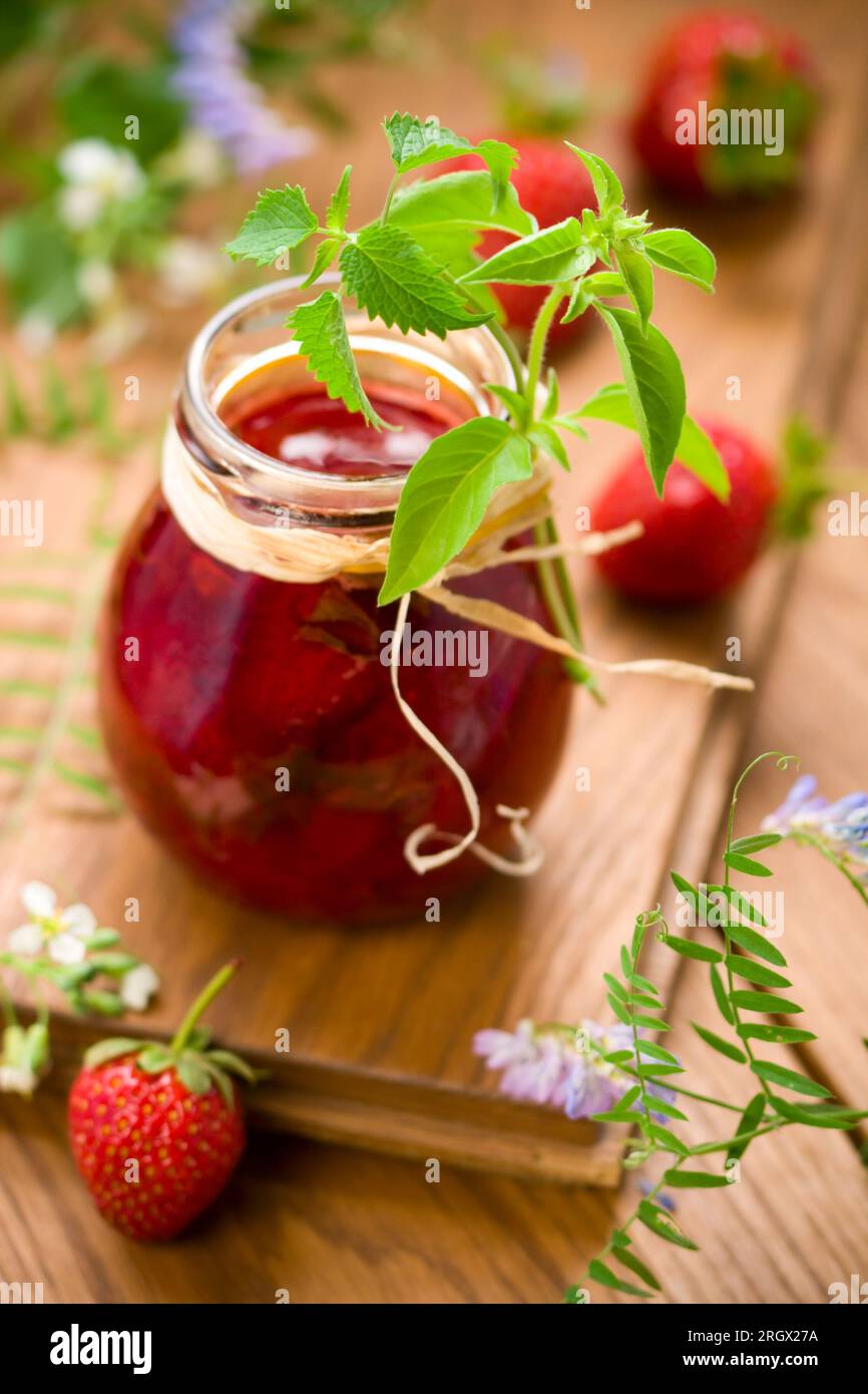 Ein Glas Erdbeermarmelade mit Basilikum und Minze Stockfoto