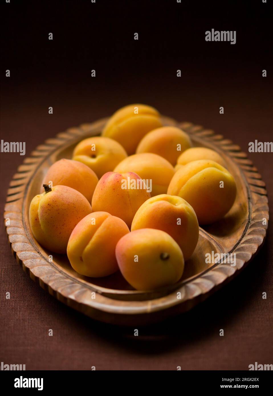 Frische reife Aprikosen auf einem Holzteller Stockfoto