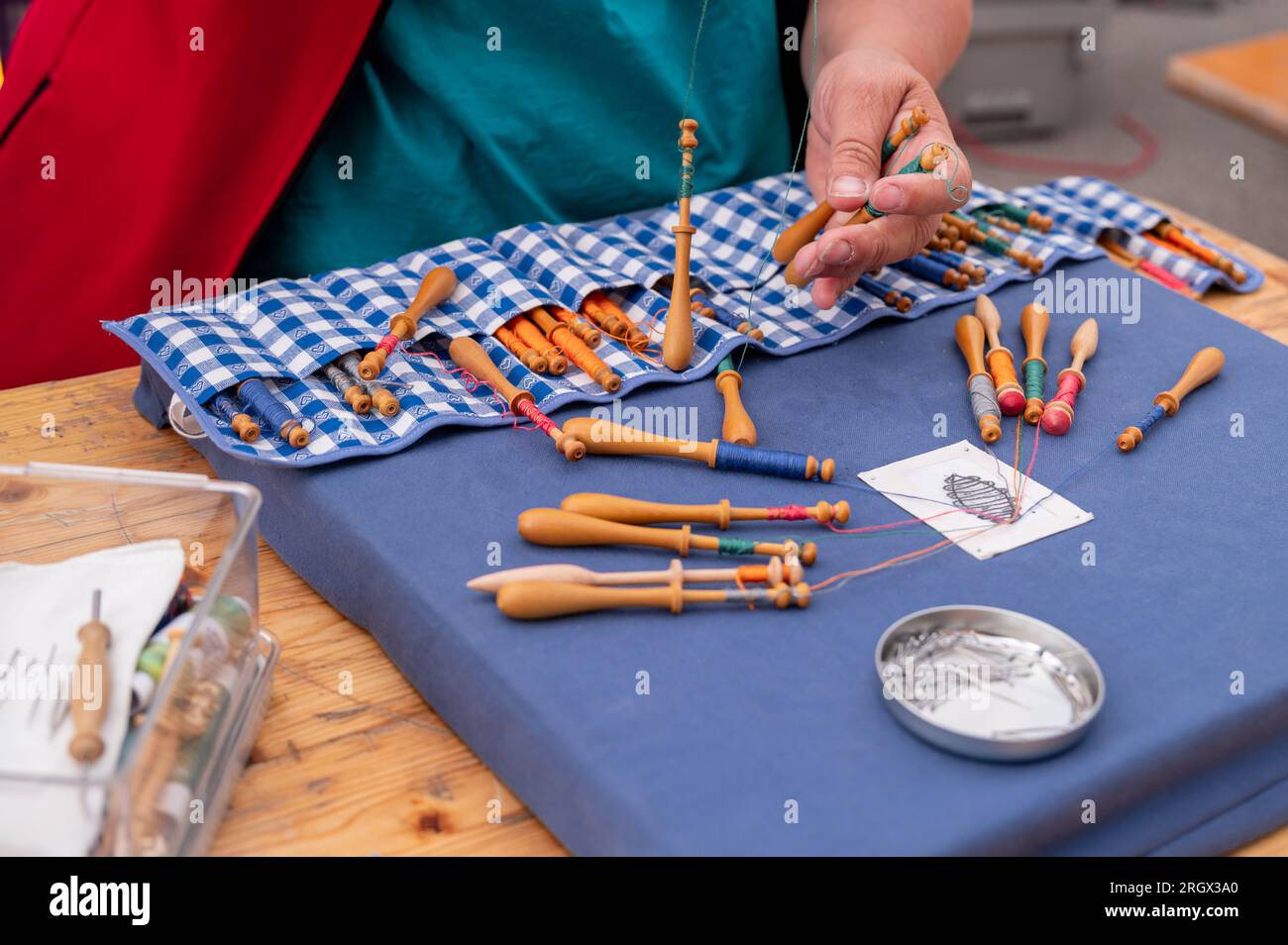Hände von Menschen, die Spulenspitzen vorbereiten und herstellen. Farbenfrohe Spitzenfäden. Freizeitaktivität. Stockfoto