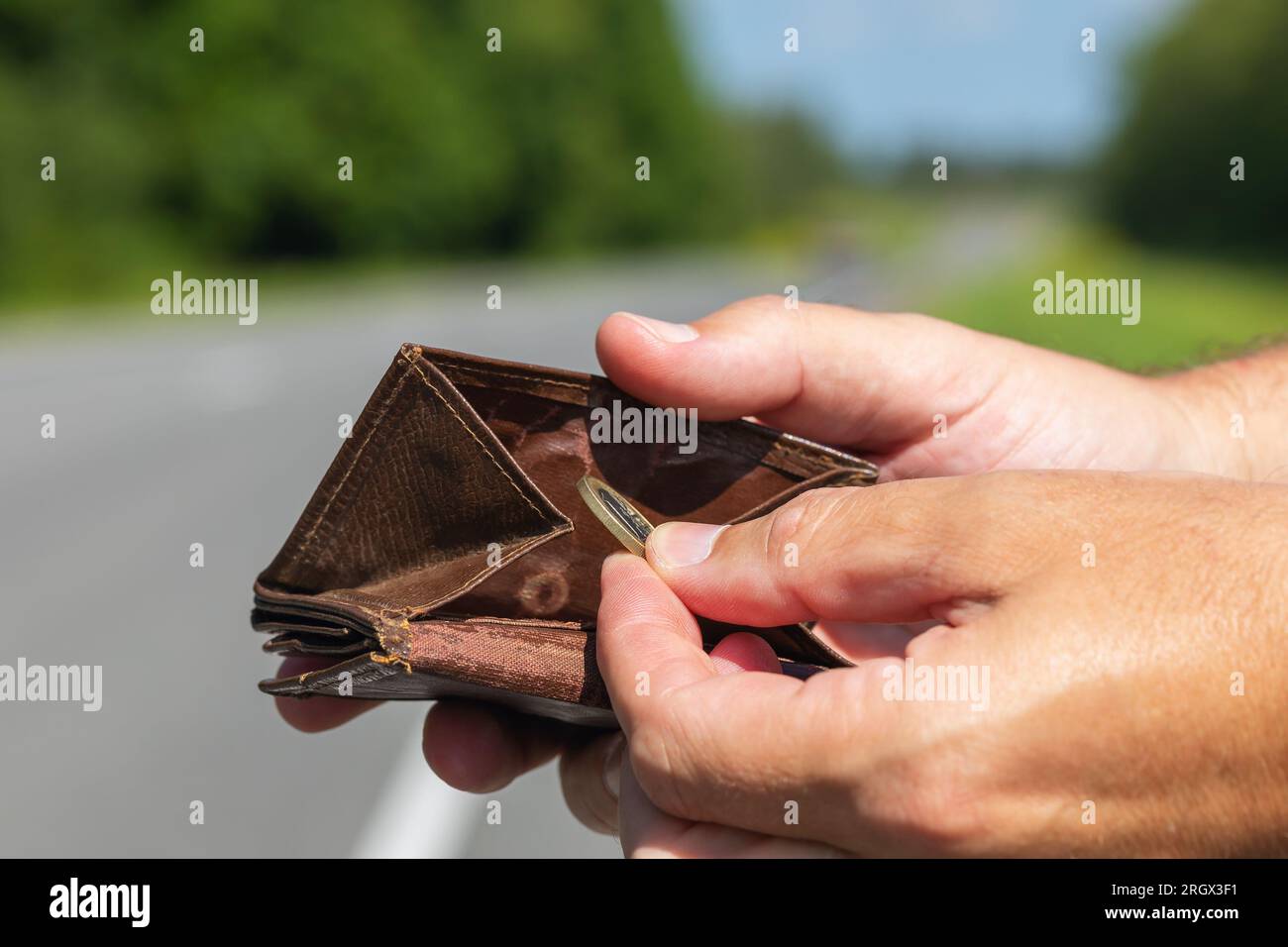 Ein Mensch nimmt einen Euro aus seiner Brieftasche, steht auf der Straße, ein Konzept von Geldmangel für Reisen Stockfoto