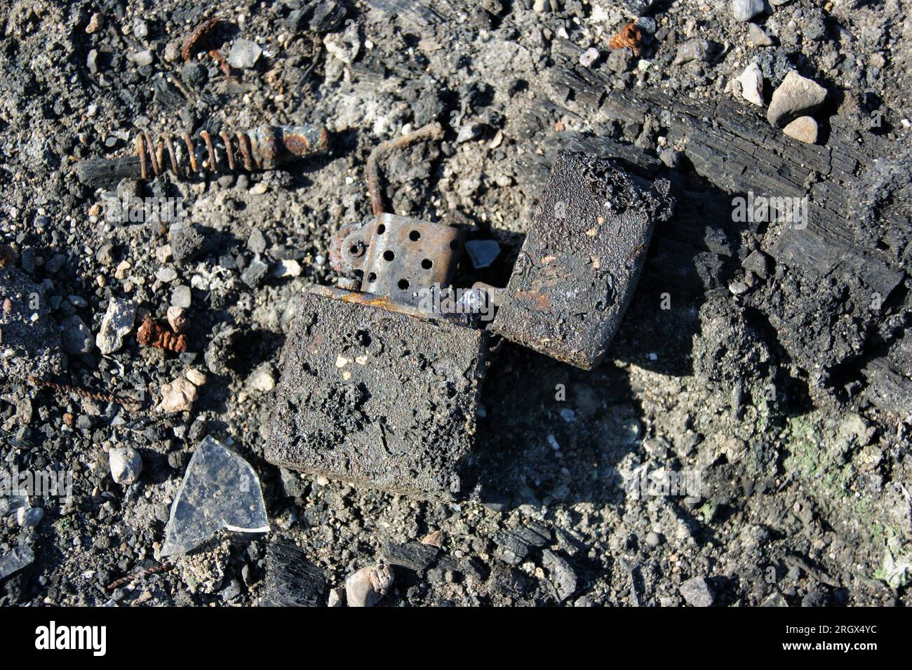 Feuerzeug aus gebranntem Metall in Asche. Die Folgen des Feuers. Nahaufnahme. Stockfoto