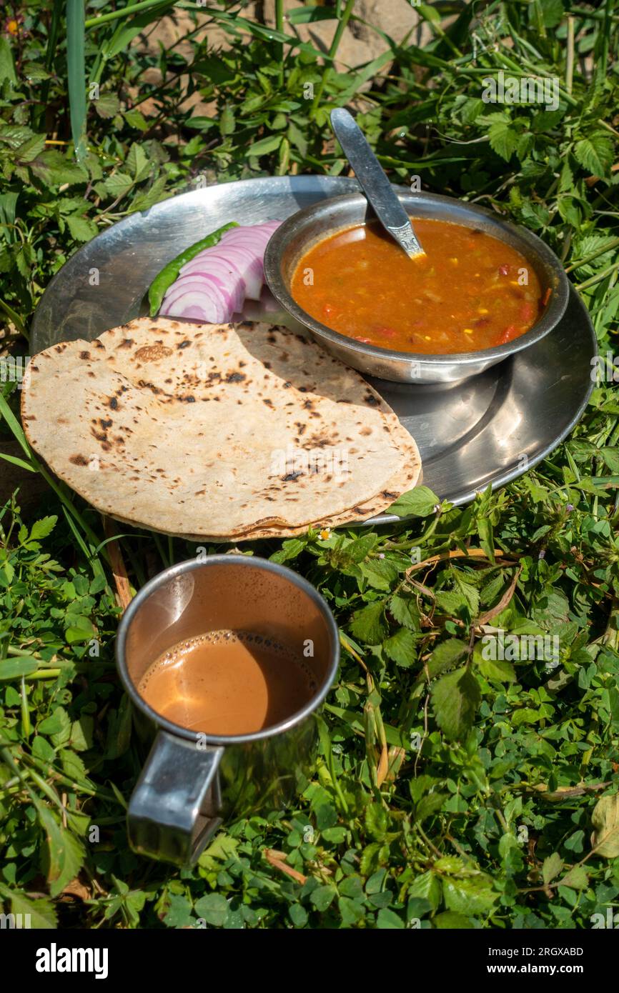 Indische Roti-Sabzi (indisches Brot und Gemüse-Curry)-Speiseplatte und Tee im Freien während des Campings im Himalaya. Uttarakhand Indien. Stockfoto
