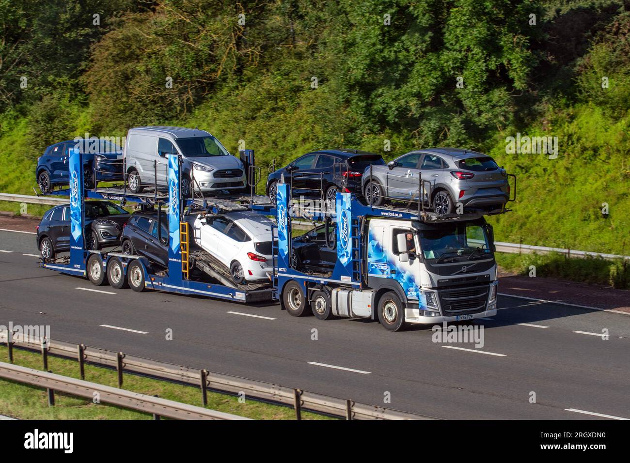 Die neuen Ford Puma Cars werden auf dem CT27 167 8 Car Transporter Indespension Anhänger und 2016 Volvo FH Diesel Truck 12777 cm3 ausgeliefert; sie fahren mit hoher Geschwindigkeit auf der Autobahn M6 im Großraum Manchester, Großbritannien Stockfoto