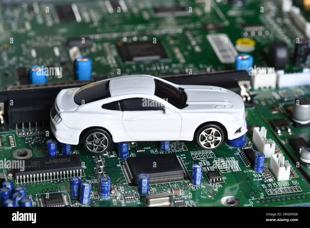 Spielzeugautos auf Elektronikplatine und Mikrochip. Konzeptbild für Halbleiterknappheit, die die Produktion in der Automobilindustrie stört. Stockfoto