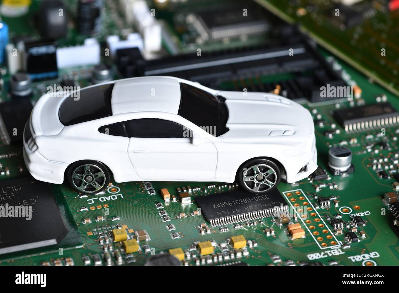Spielzeugautos auf Elektronikplatine und Mikrochip. Konzeptbild für Halbleiterknappheit, die die Produktion in der Automobilindustrie stört. Stockfoto