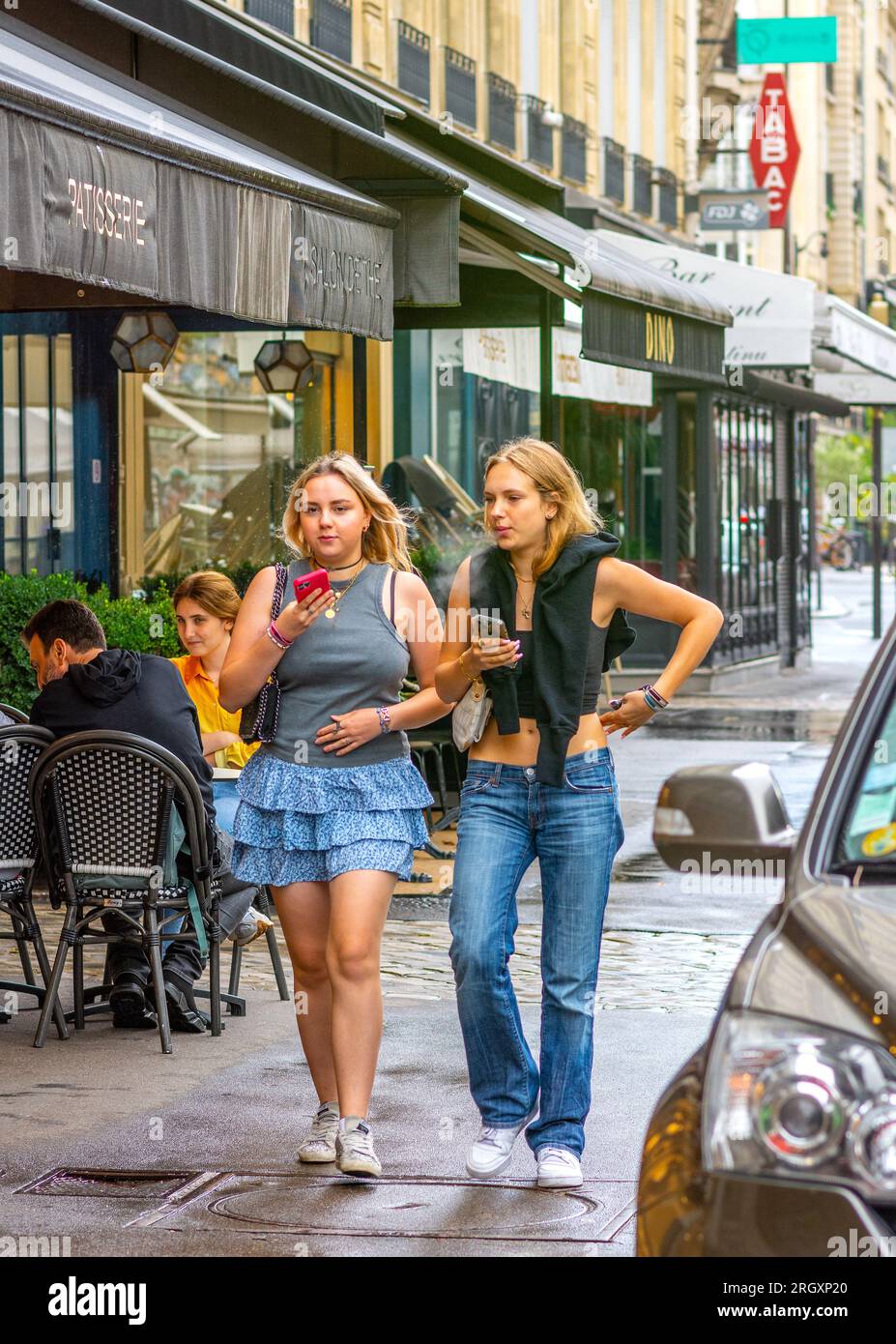 Zwei zwanglos gekleidete Teenager-Mädchen, die auf dem Bürgersteig der Stadt spazieren - Paris 16, Frankreich. Stockfoto