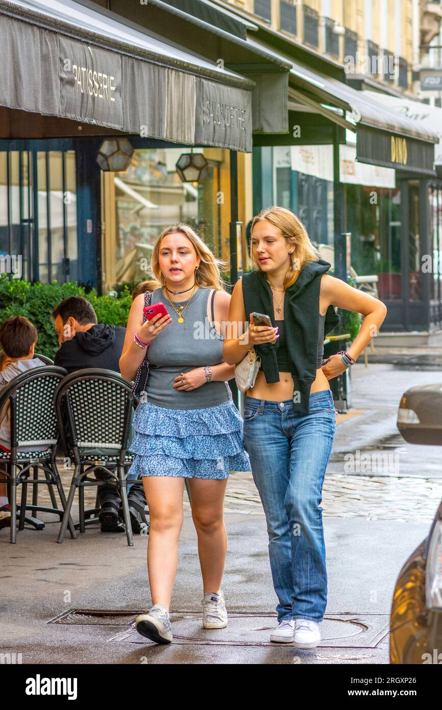 Zwei zwanglos gekleidete Teenager-Mädchen, die auf dem Bürgersteig der Stadt spazieren - Paris 16, Frankreich. Stockfoto