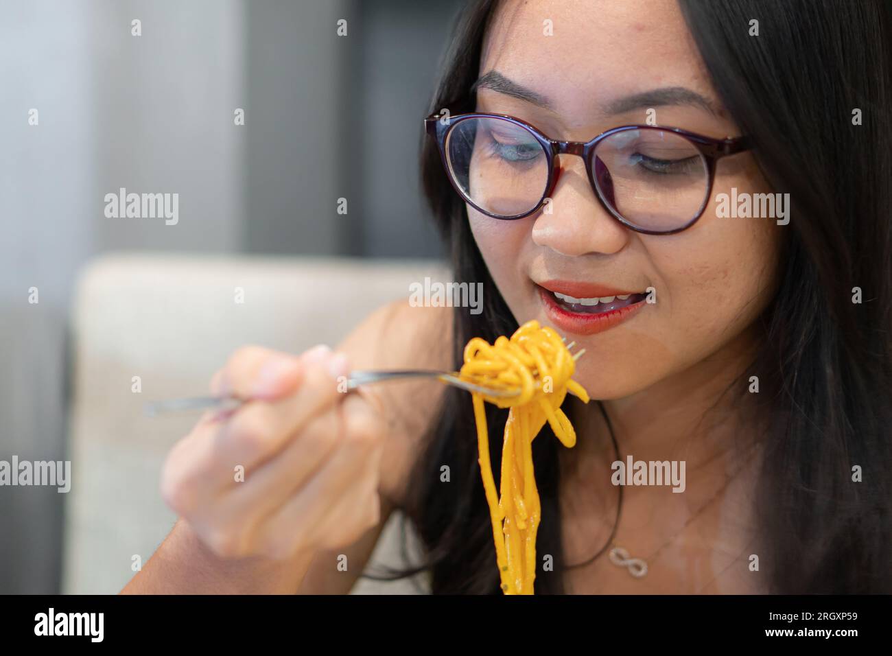 Schöne Frau essen Pasta auf den Tisch gegen verschwommenen Hintergrund Stockfoto