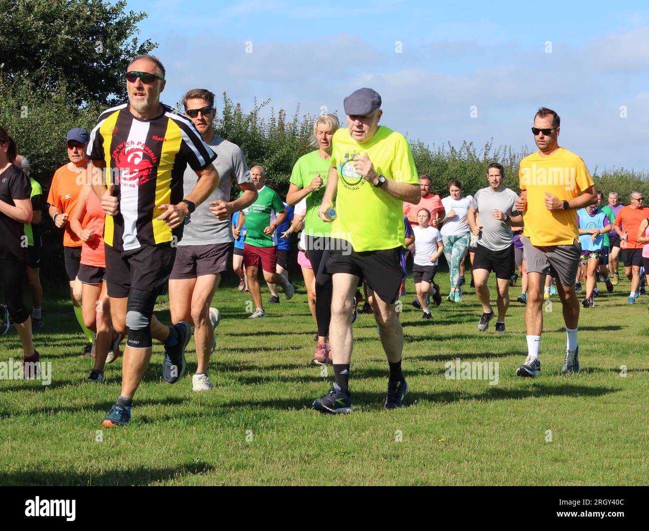 Kesgrave, Suffolk - 12. August 2023 : Kesgrave's 400. Park Run Event auf dem Millennium Field. Ein älterer Mann mit einer flachen Mütze, der stark läuft. Stockfoto