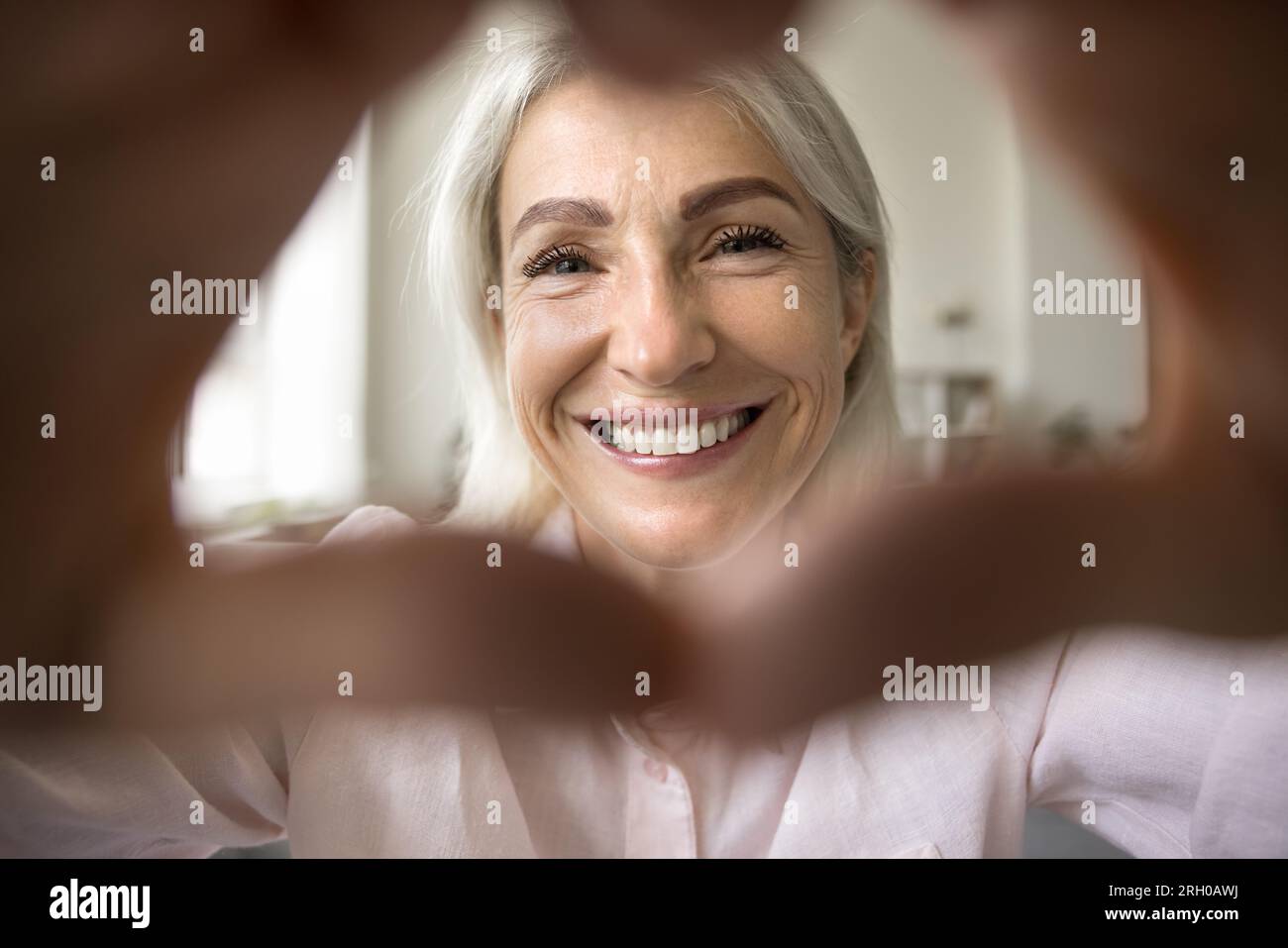 Fröhliche, ziemlich reife Frau, die mit einem Zahnlächeln in die Kamera schaut Stockfoto