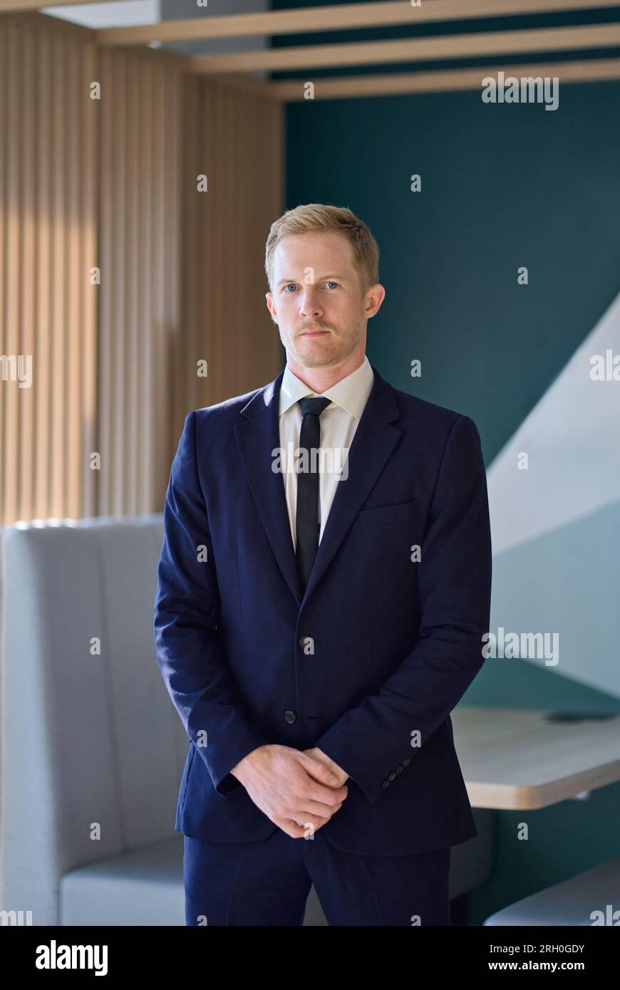 Selbstbewusster junger Geschäftsmann, der im Amt steht. Vertikales Hochformat. Stockfoto