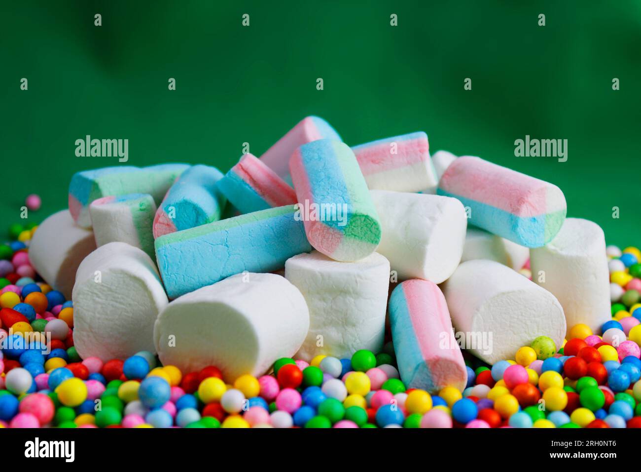 Marshmallows über farbigen Kugeln mit grünem Hintergrund Stockfoto