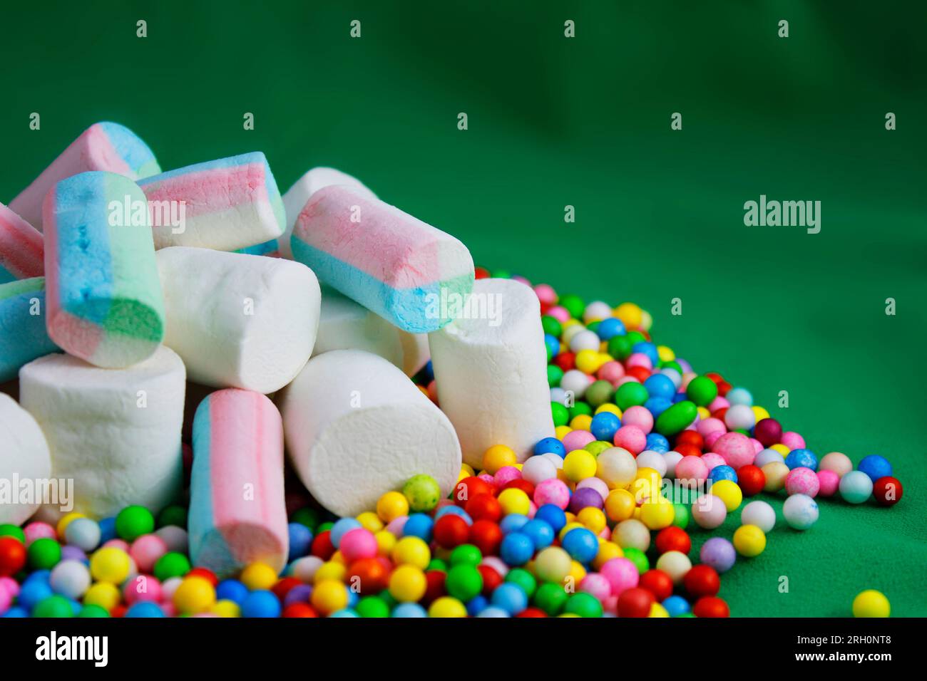 Marshmallows über farbigen Kugeln mit grünem Hintergrund Stockfoto