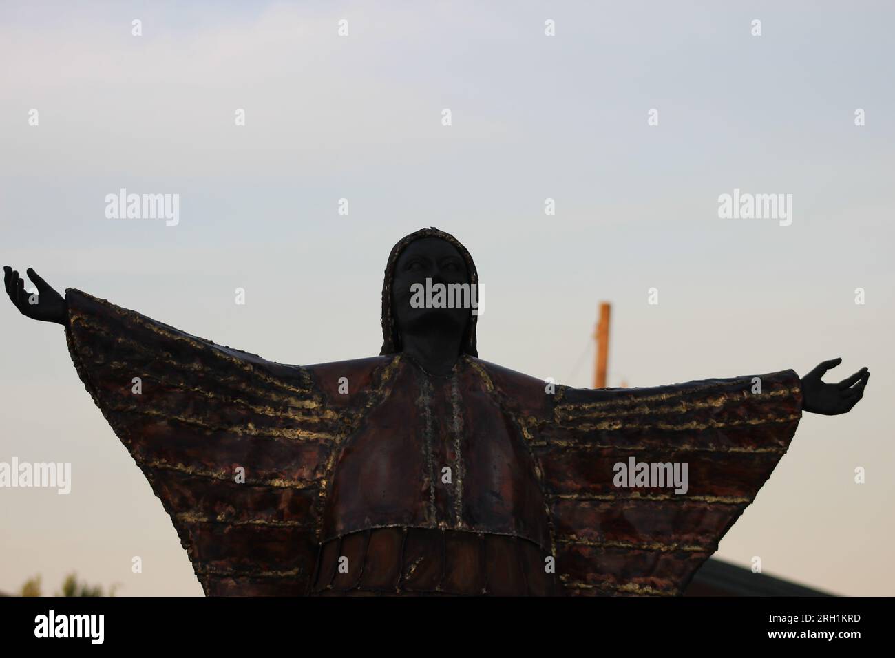 Ein brillantes Bronzestaat, das den unerschütterlichen Geist und die Anmut einer einheimischen Frau einfängt, die Hände in den Himmel gestreckt hat. Stockfoto