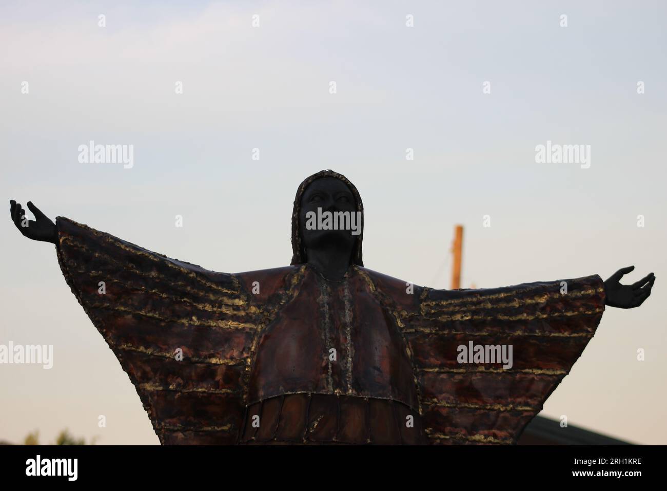 Ein brillantes Bronzestaat, das den unerschütterlichen Geist und die Anmut einer einheimischen Frau einfängt, die Hände in den Himmel gestreckt hat. Stockfoto