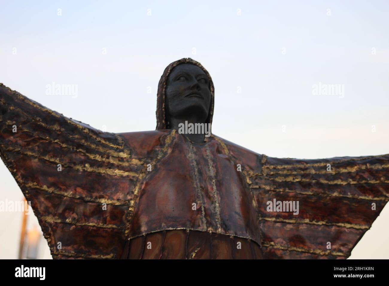 Ein brillantes Bronzestaat, das den unerschütterlichen Geist und die Anmut einer einheimischen Frau einfängt, die Hände in den Himmel gestreckt hat. Stockfoto