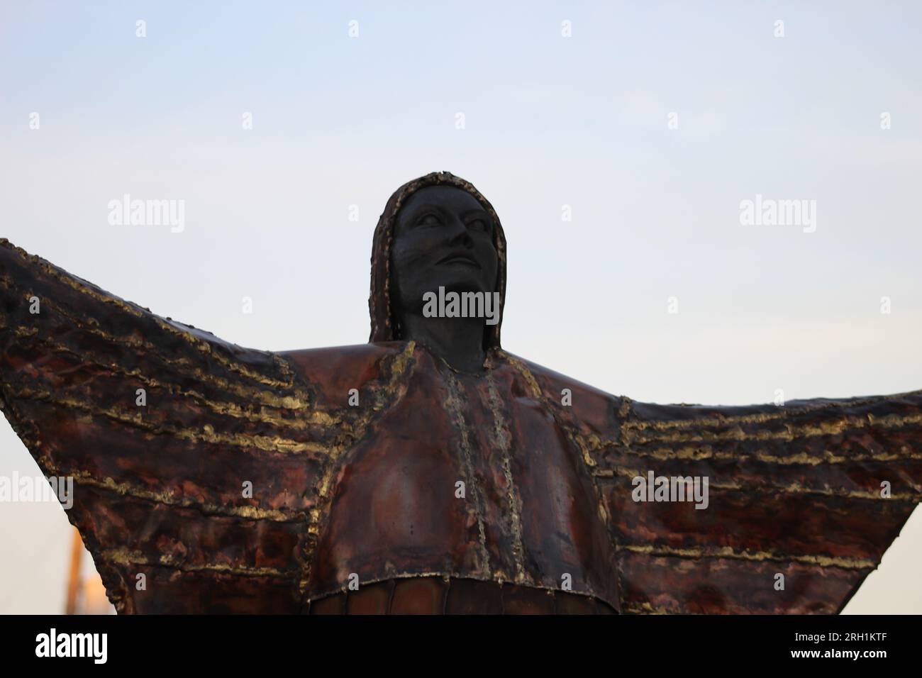 Ein brillantes Bronzestaat, das den unerschütterlichen Geist und die Anmut einer einheimischen Frau einfängt, die Hände in den Himmel gestreckt hat. Stockfoto