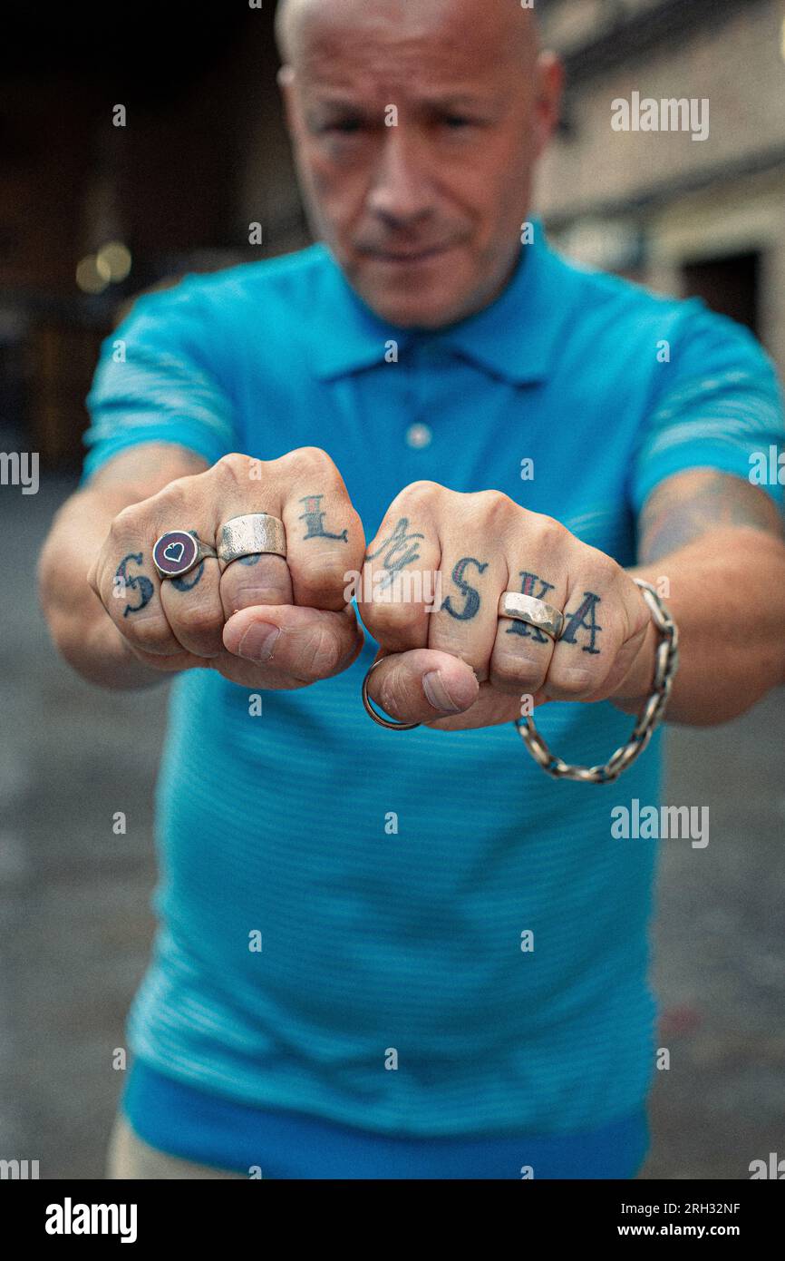 Ein Mann, der seine Faust zeigt, mit Ringen mit Seele und Ska Tattoo über den Fingern in london, großbritannien Stockfoto