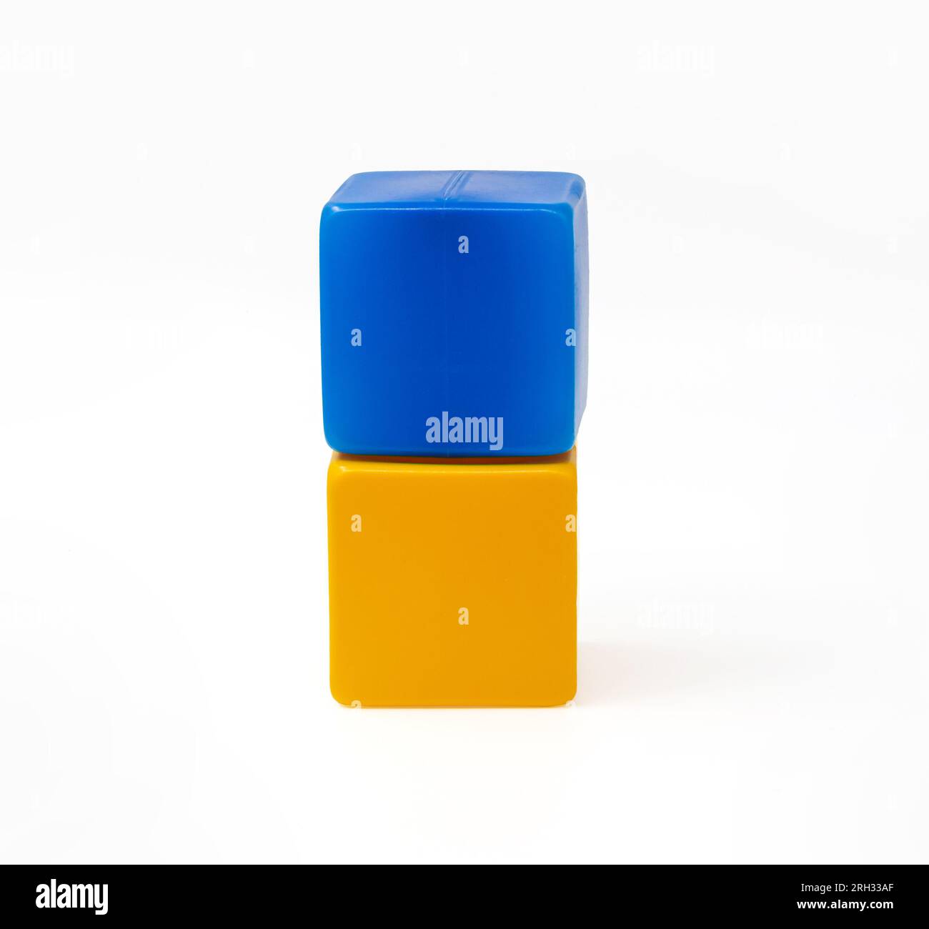 Bunte Kunststoffwürfel für Kinderspiele. Blauer Würfel auf gelbem Würfel. Eins gegen eins. Foto in hoher Qualität. Stockfoto