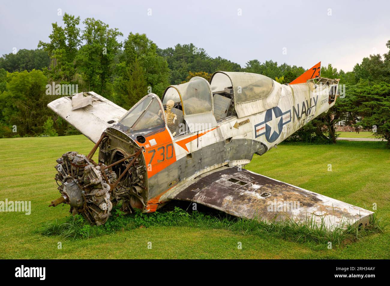 Wartburg, Tennessee, USA - 29. Juli 2023: Ein altes Navy-Trainerflugzeug mit mehreren fehlenden Teilen sitzt auf einem Rasen mit einem gefälschten Skelett im Cockpit. Stockfoto