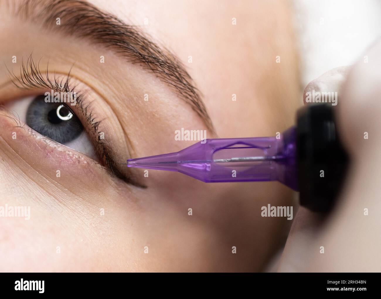 Mikropigmentierungskonzept. Kosmetikerin, die eine permanente Make-up-Eyeliner-Prozedur bei jungen Frauen durchführt Stockfoto