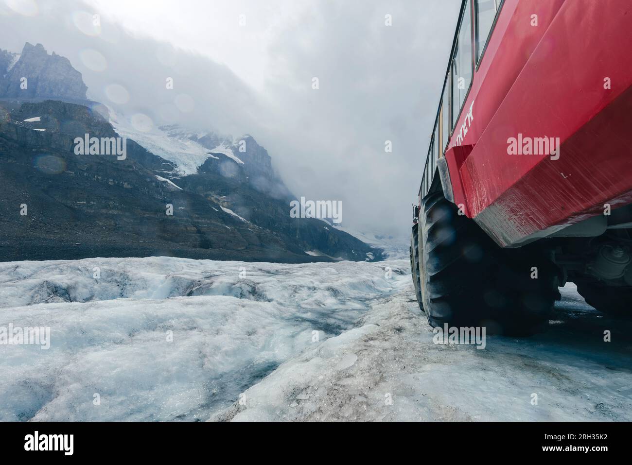 Nahaufnahme des Reifens eines Touristeneisbusses und des Athabasca-Gletschers auf dem Icefields Parkway in Alberta, Kanada Stockfoto