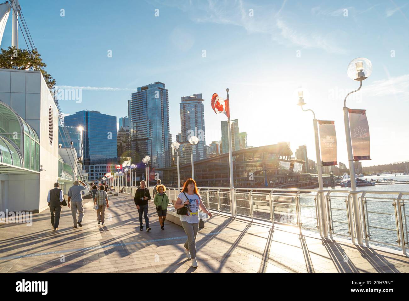 Die Leute genießen einen abendlichen Spaziergang in der Sommersonne entlang des Pier in Coal Harbour, Vancouver, Kanada Stockfoto