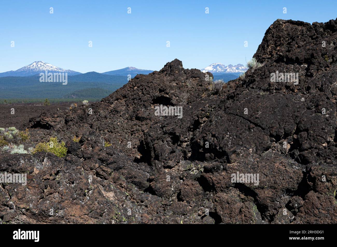 Das Lavafeld am Newberry Volcanic National Monument erstreckt sich westlich in Richtung Mt. Bachelor, South Sister, Broken Top und North Sister Vulkane in des Stockfoto