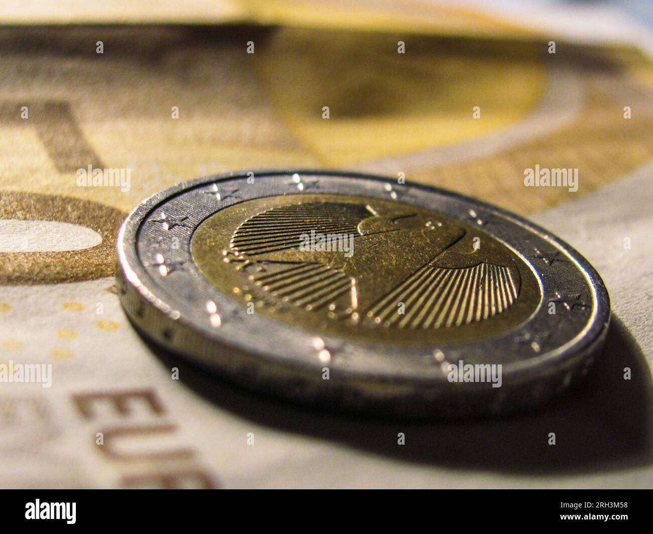 Währungskontrast: Die Euro-Münze ruht auf einer 50-Euro-Banknote Stockfoto
