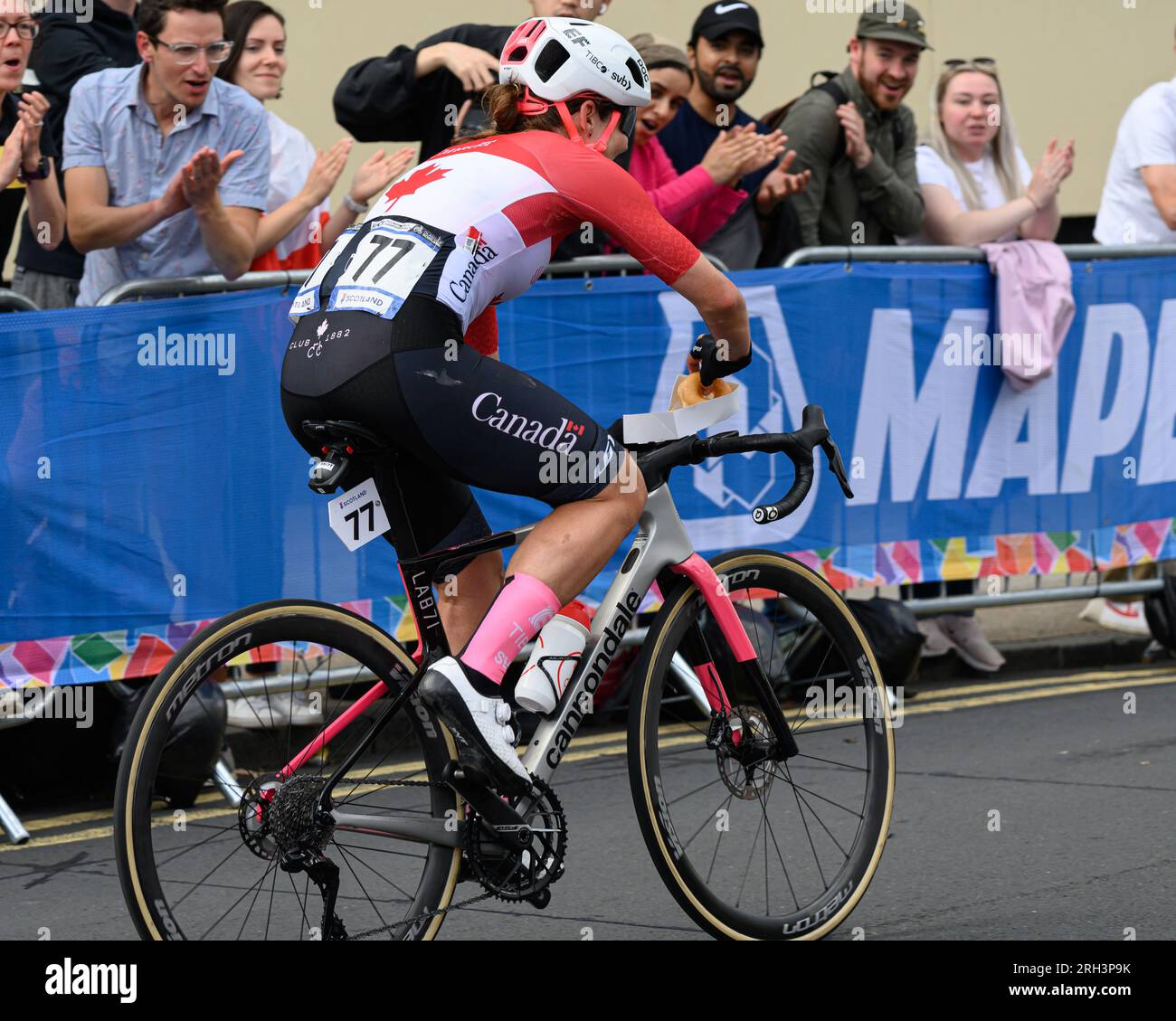 Glasgow, Schottland. 13. Aug. 2023. Ein kanadischer Teilnehmer, der beim UCI Womens Elite Cycling Road Race eine Schachtel Donuts von einem Zuschauer annimmt Stockfoto