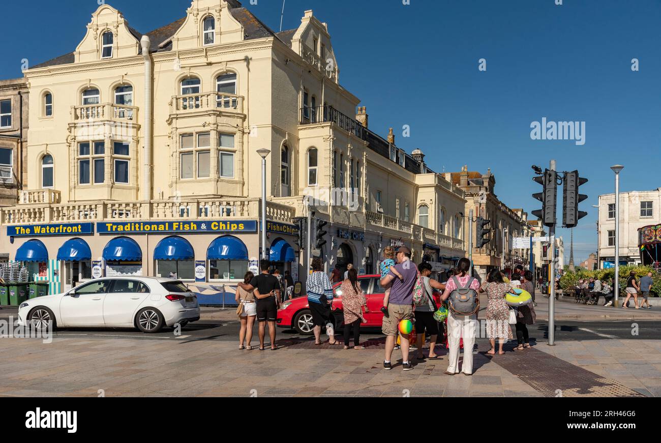 Weston Super Mare, Somerset, England, Großbritannien. 25. Juni 2023 Urlauber überqueren die Straße am Strand in Richtung Stadtzentrum, Weston. Stockfoto
